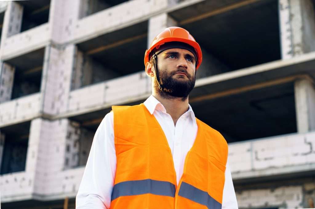 Commercial Property Insurers builder wearing hardhat and safety vest standing on a commercial construction site 1024x682 - Commercial Property Insurers